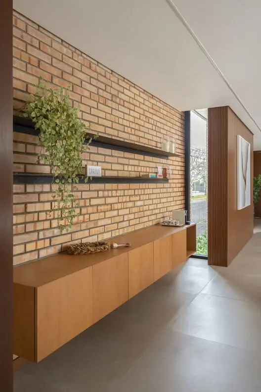 Interior contemporâneo com parede de tijolos ecológicos e marcenaria em madeira