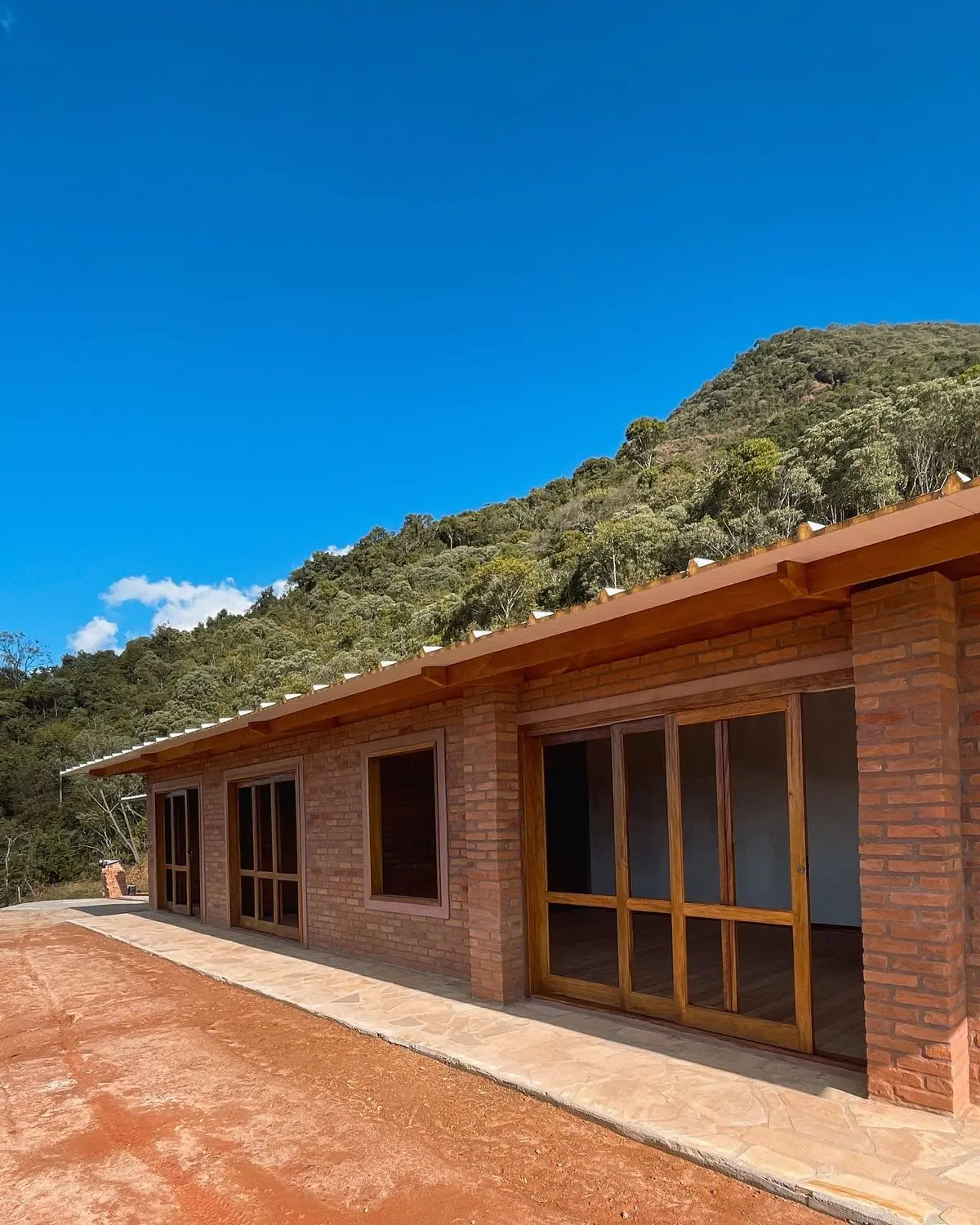 Casa térrea construída com tijolos ecológicos aparentes em meio à natureza
