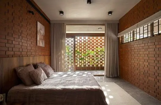 Quarto com paredes de tijolos ecológicos aparentes e elementos vazados